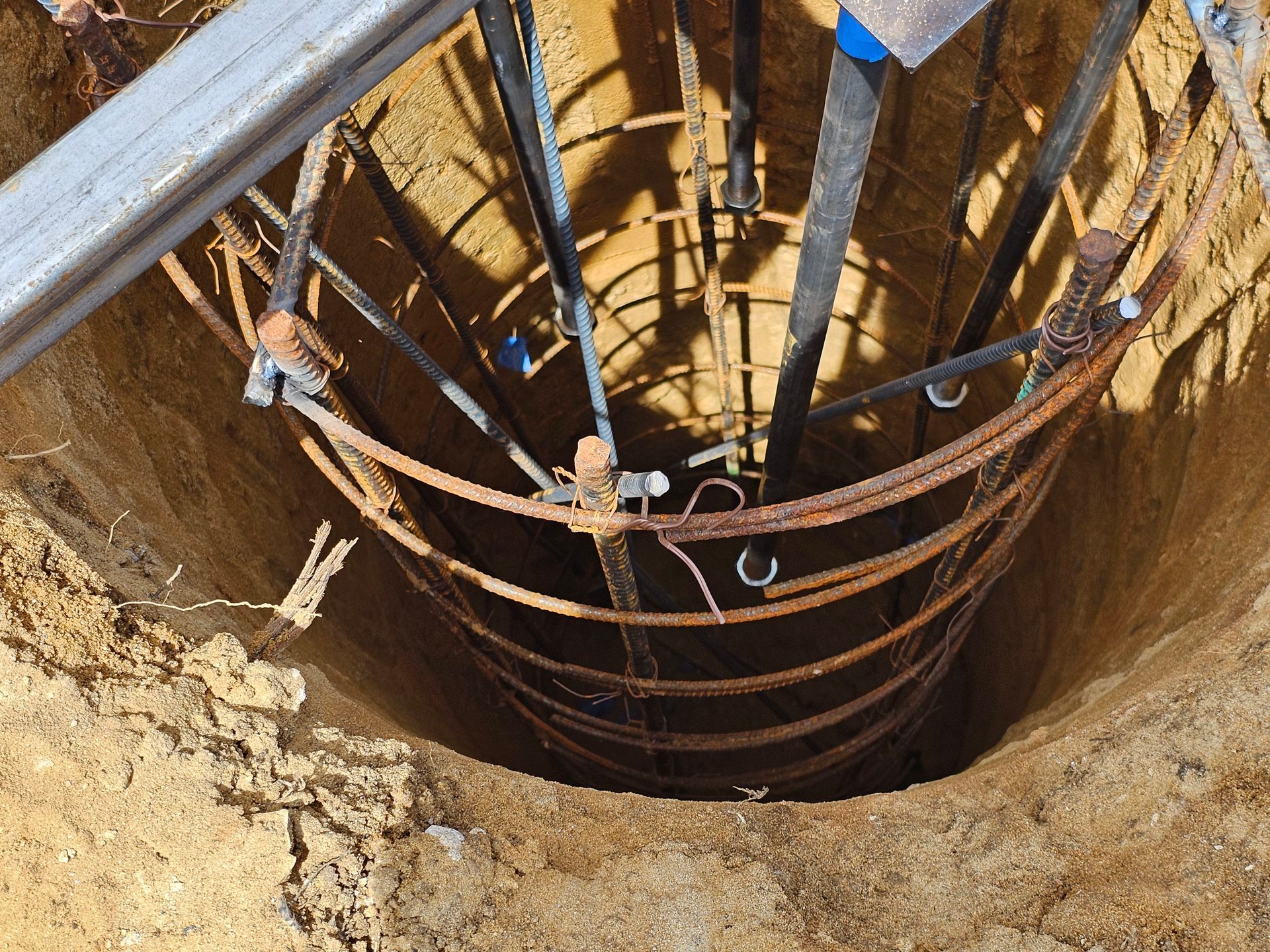 A hole in the ground with a bunch of wires coming out of it