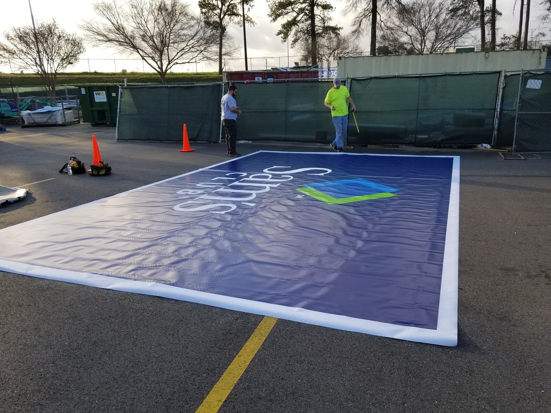A large blue sign is being painted on the ground in a parking lot.