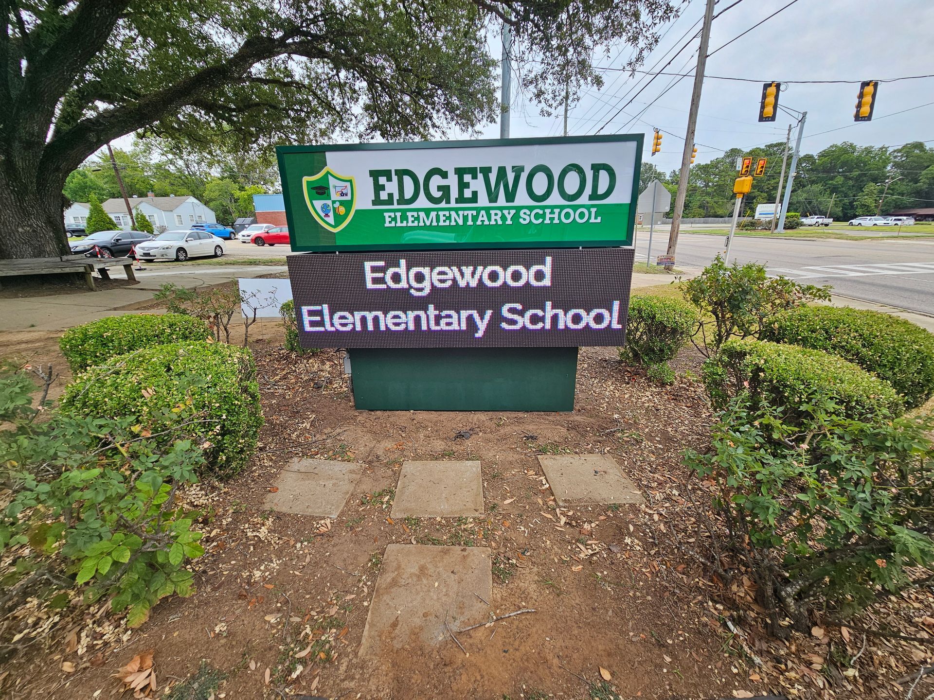 A sign for edgewood elementary school is surrounded by bushes and trees.