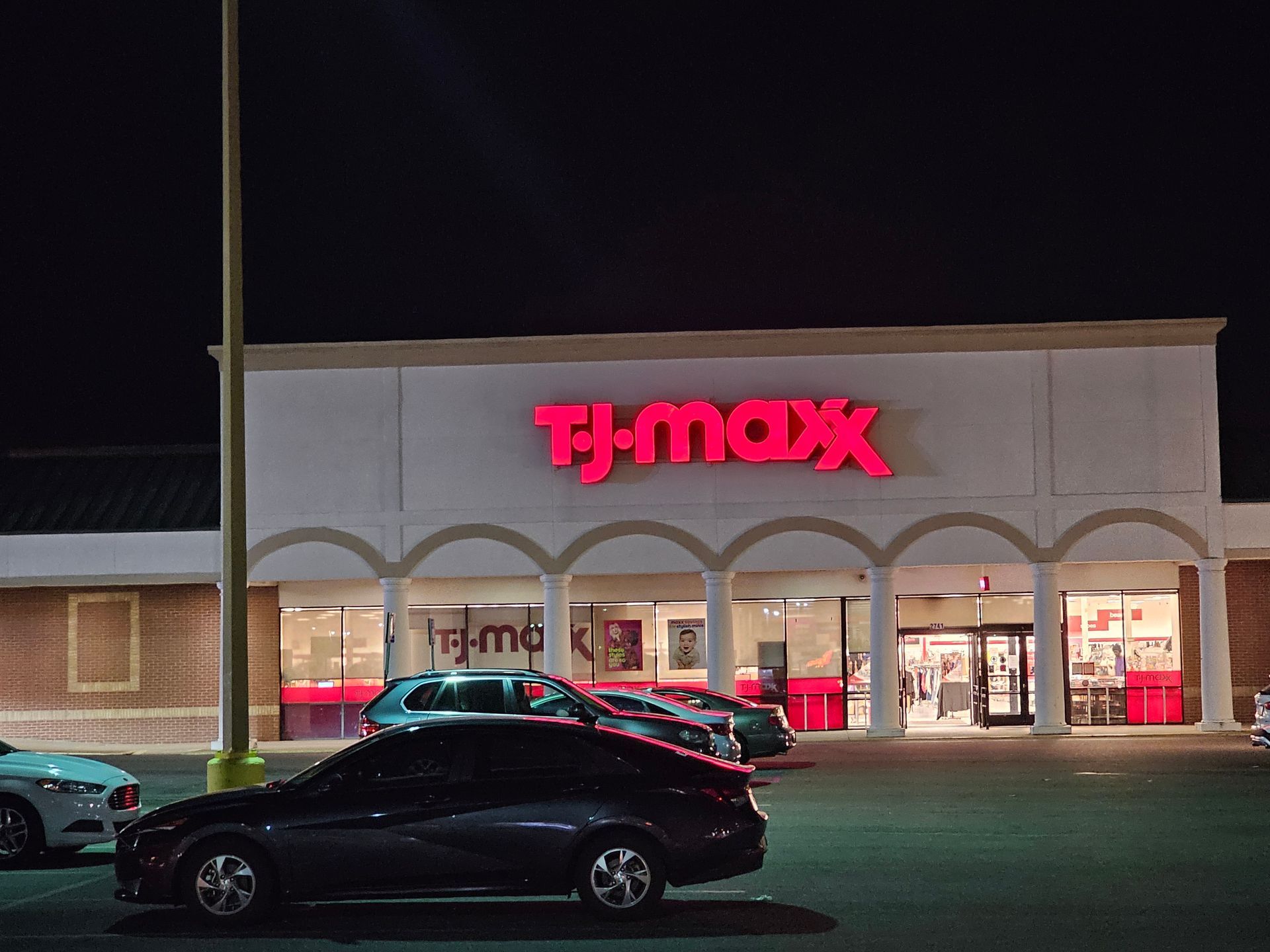Cars are parked in front of a t-max store at night