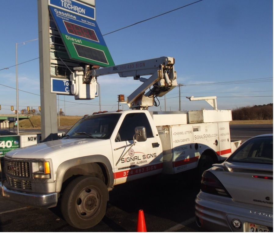 A white truck is parked in front of a sign that says triumph