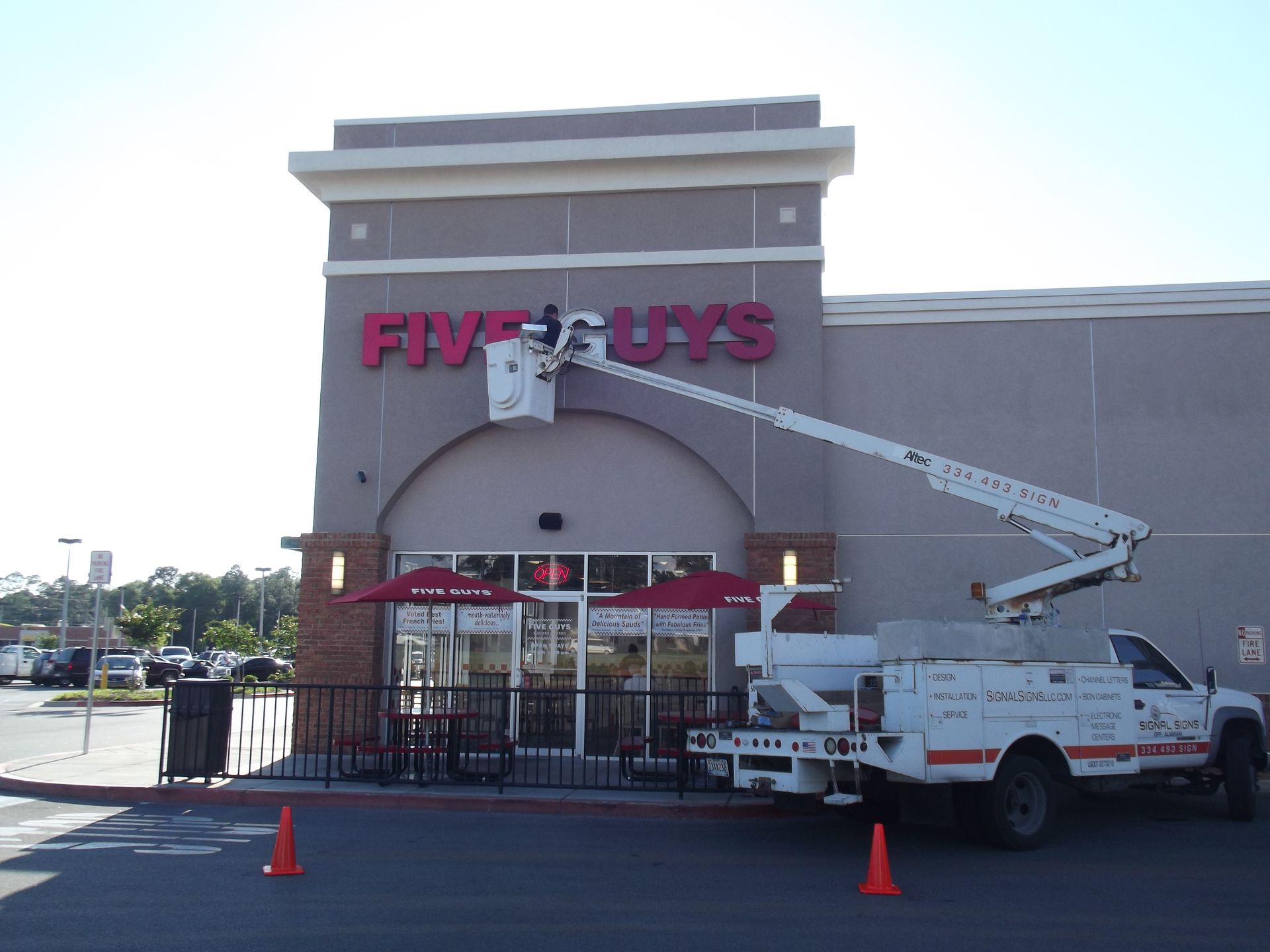 A white truck is parked in front of a five guys restaurant
