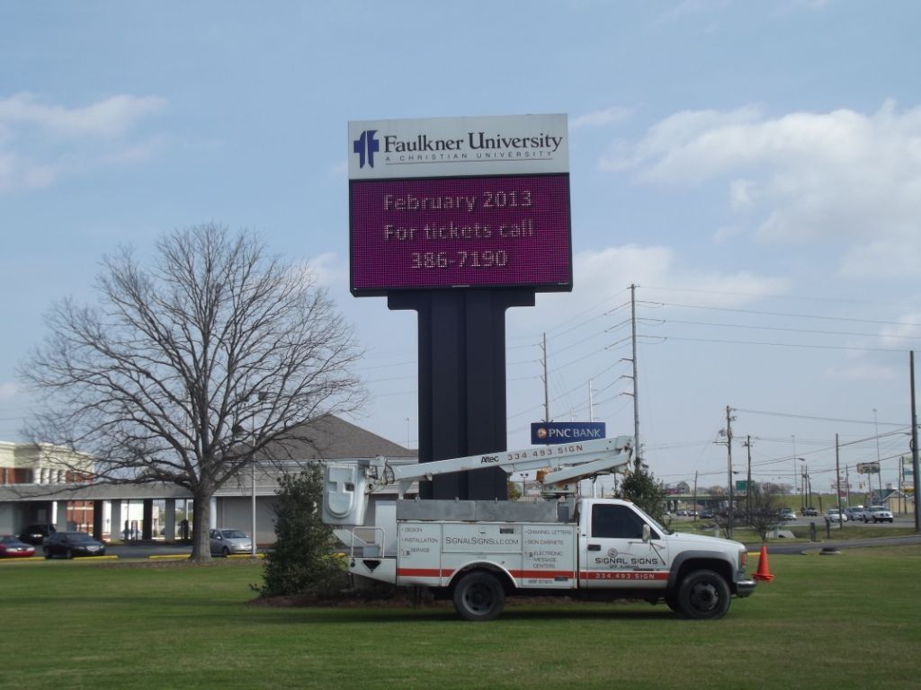 A truck is parked in front of a large sign that says leader university
