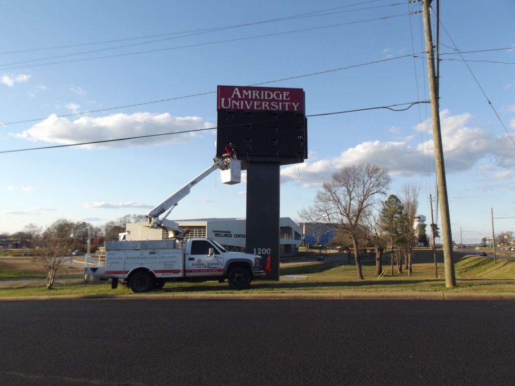 A white truck is parked in front of an ambridge university sign