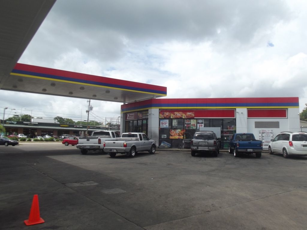 A lot of cars are parked in front of a gas station