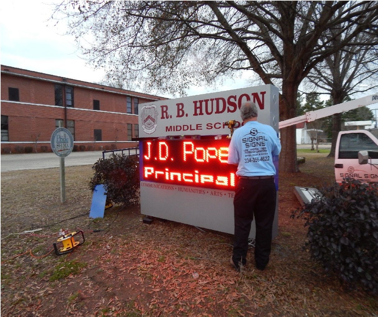 A man is working on a sign for r.b. hudson middle school