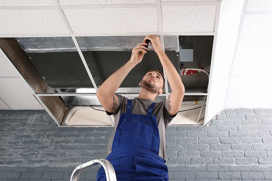 a man in overalls is fixing a ceiling fixture