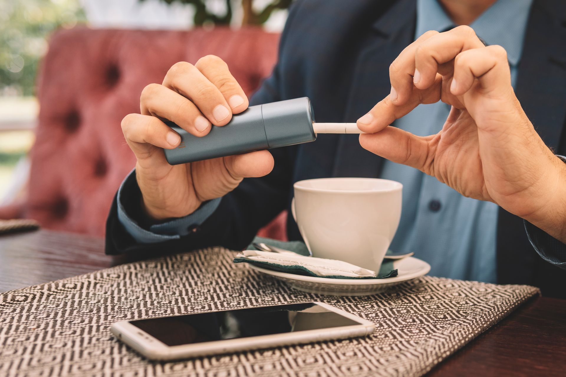 Un uomo è seduto a un tavolo con una tazza di caffè e un telefono cellulare.