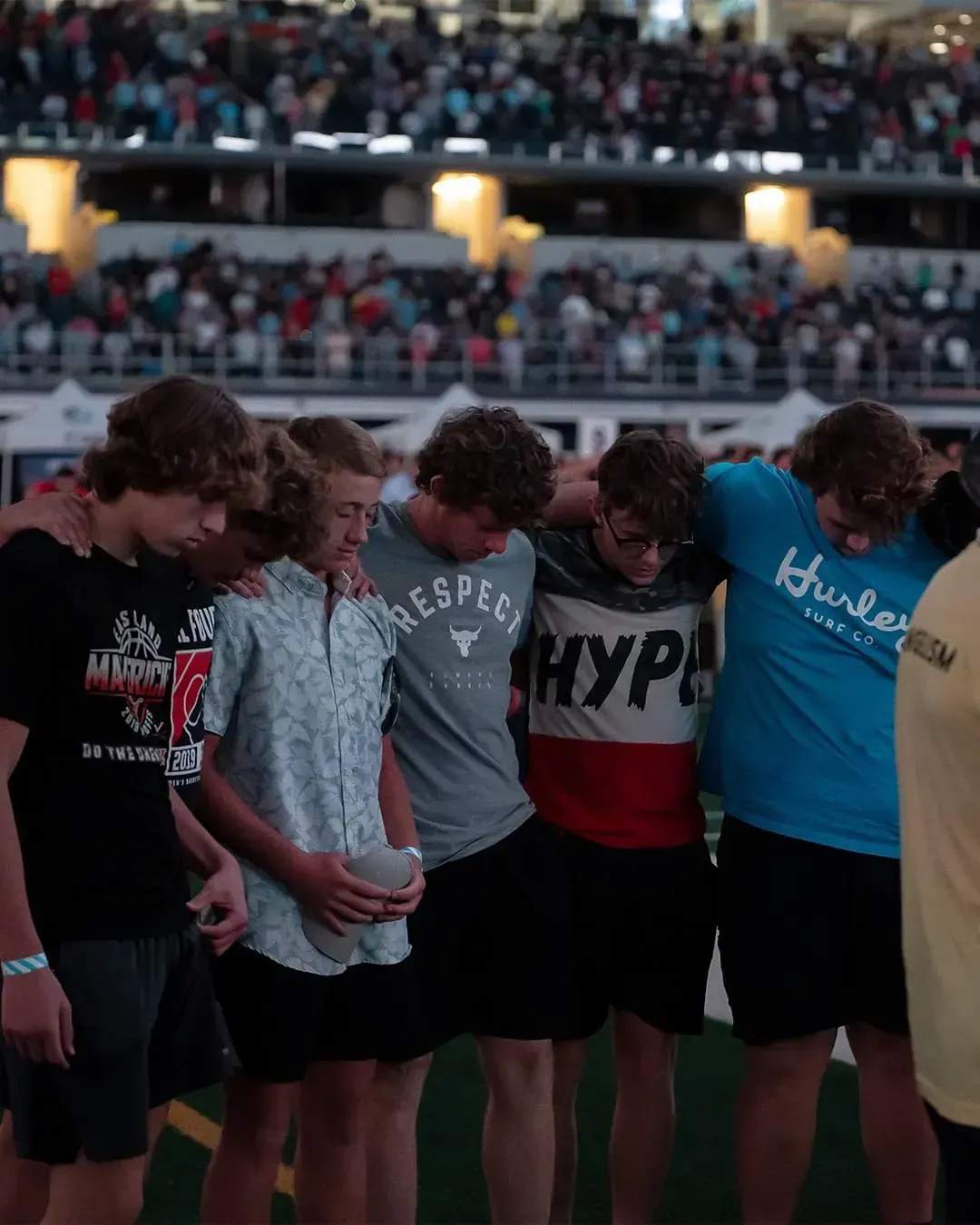A group of young men standing in a circle with one wearing a shirt that says hype