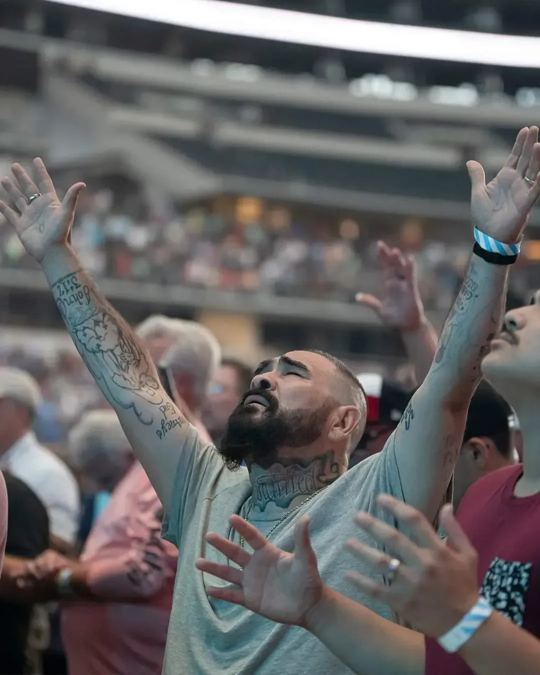A man with a beard is raising his hands in the air in a crowd of people.