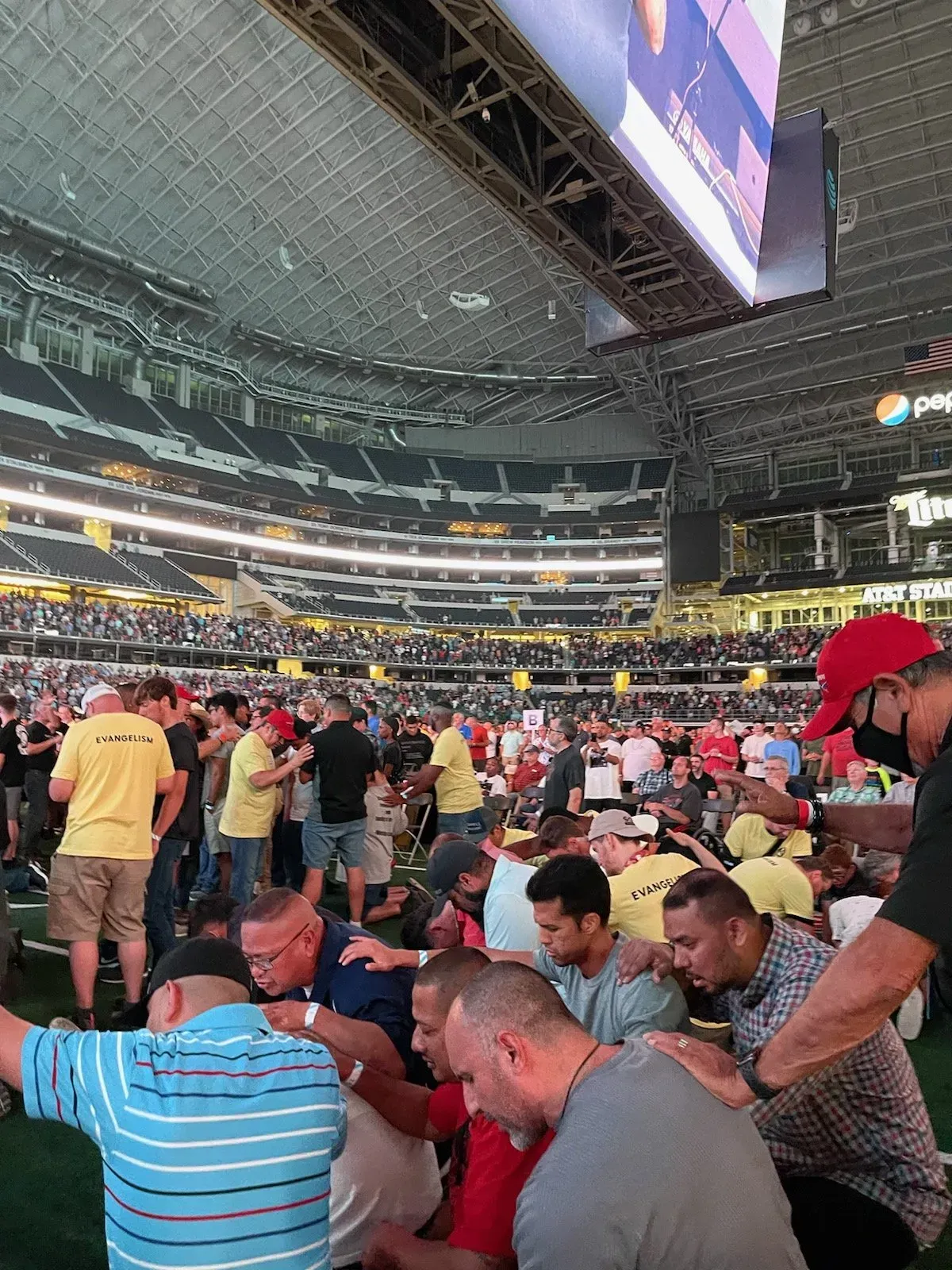 A group of men are praying in a stadium.
