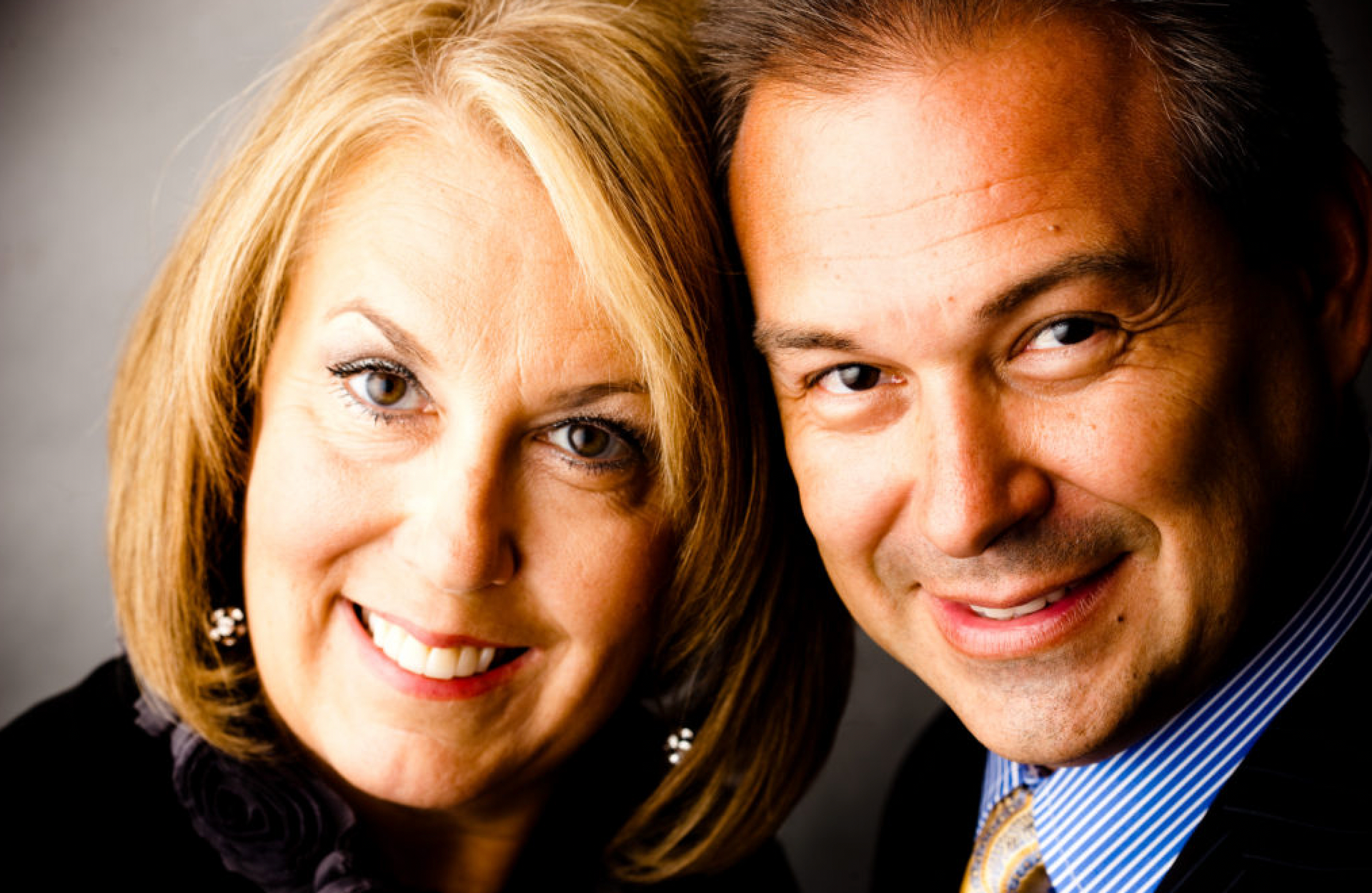 A man and a woman are posing for a picture and smiling for the camera