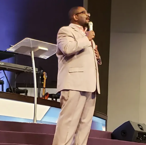 A man in a suit is speaking into a microphone