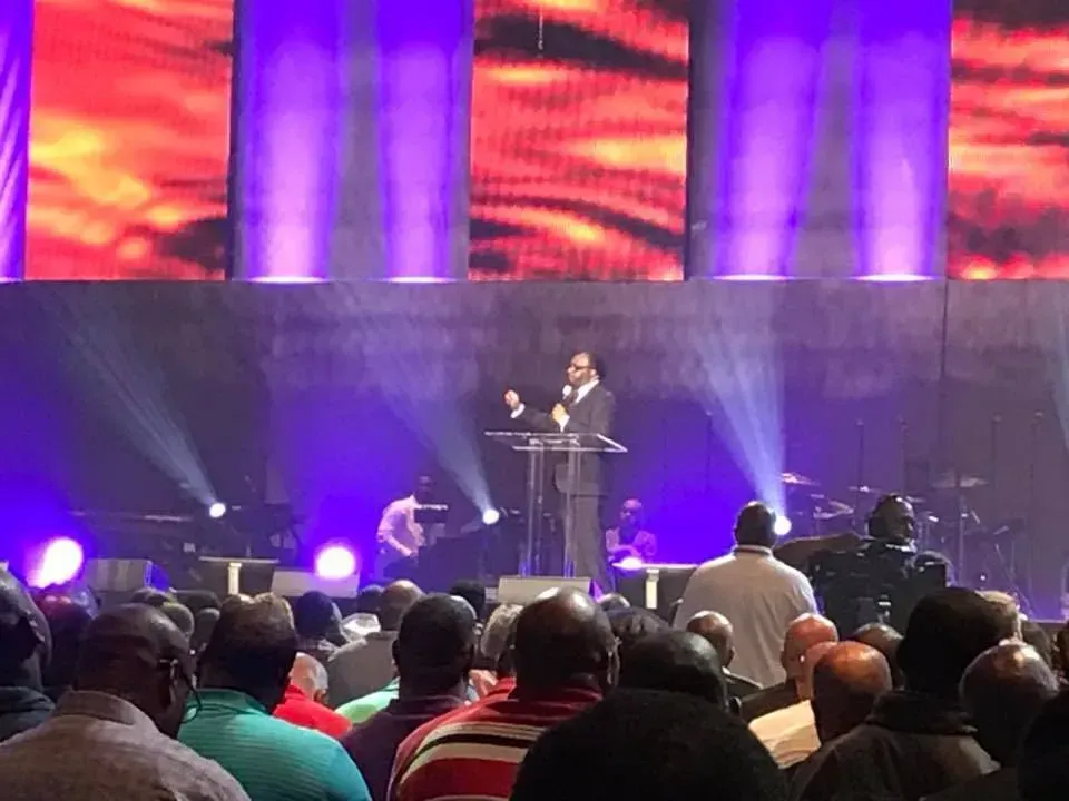 A man is standing at a podium in front of a crowd of people.