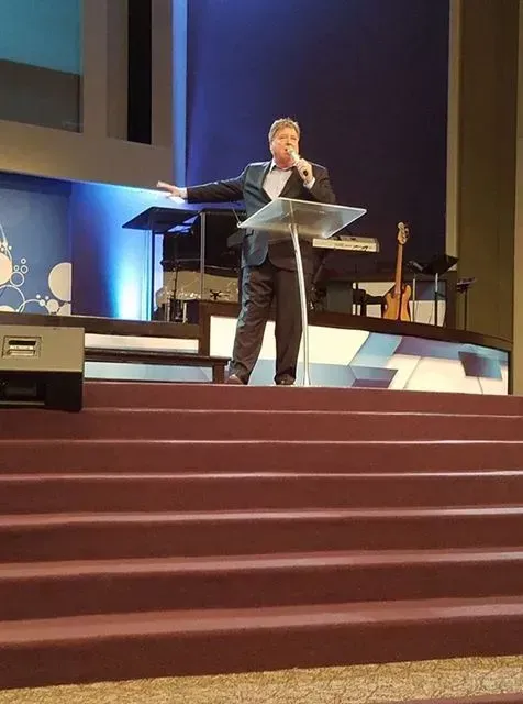 A man is standing at a podium speaking into a microphone