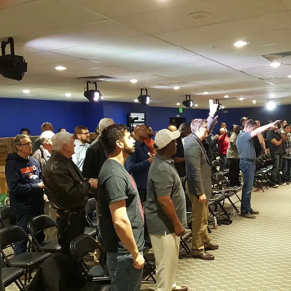 A group of people standing in a room with a blue wall