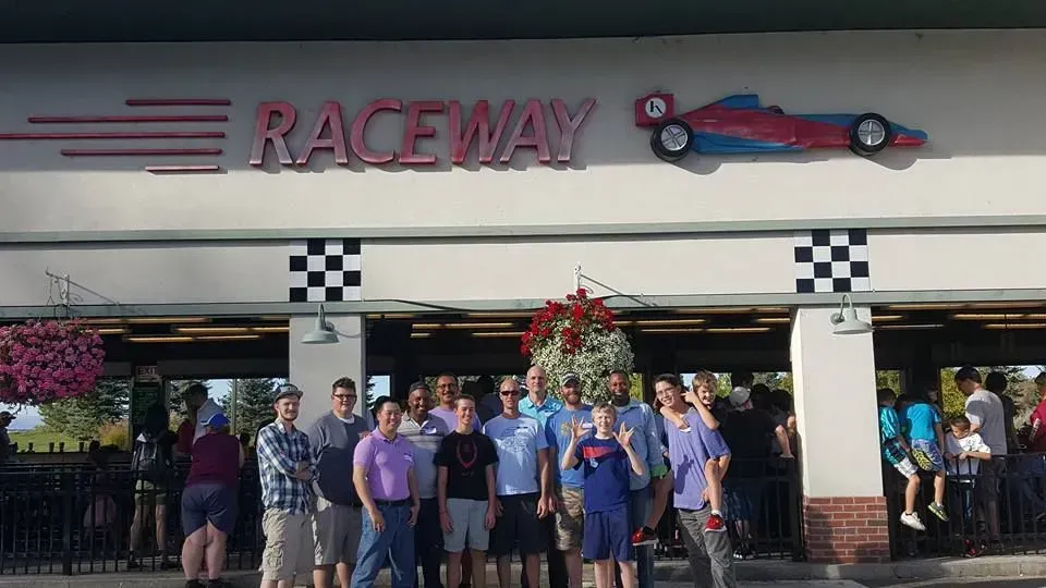 A group of people are standing in front of a raceway building.