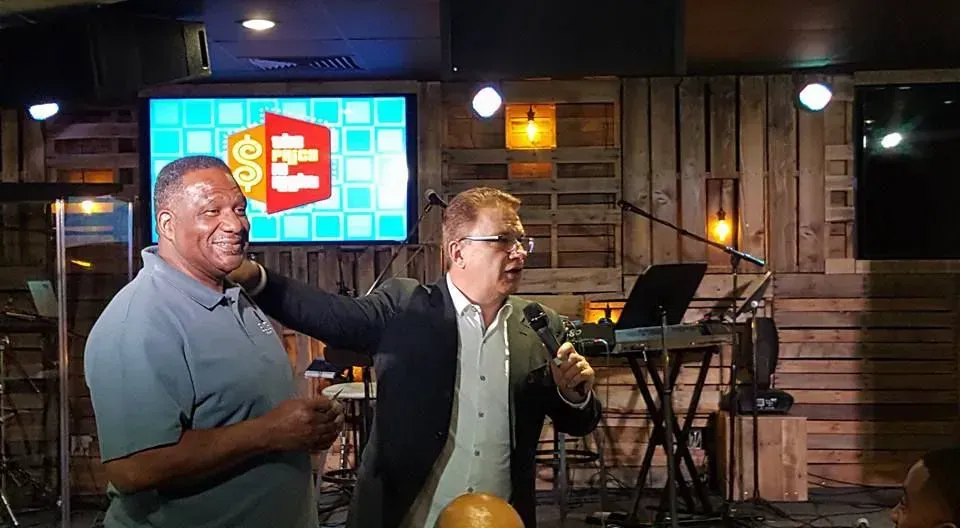 Two men are standing in front of a microphone in a room.