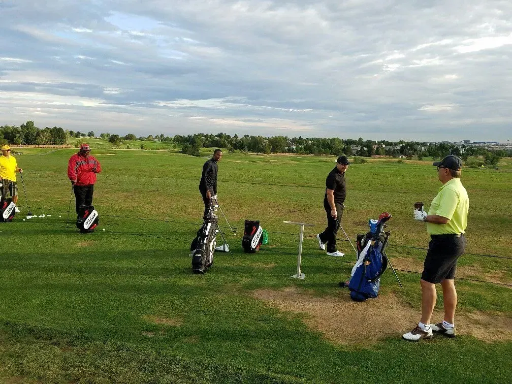 A group of men are standing on a golf course with golf bags.