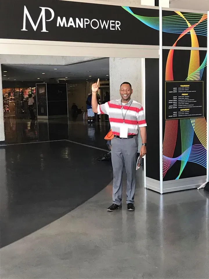 A man standing in front of a sign that says manpower