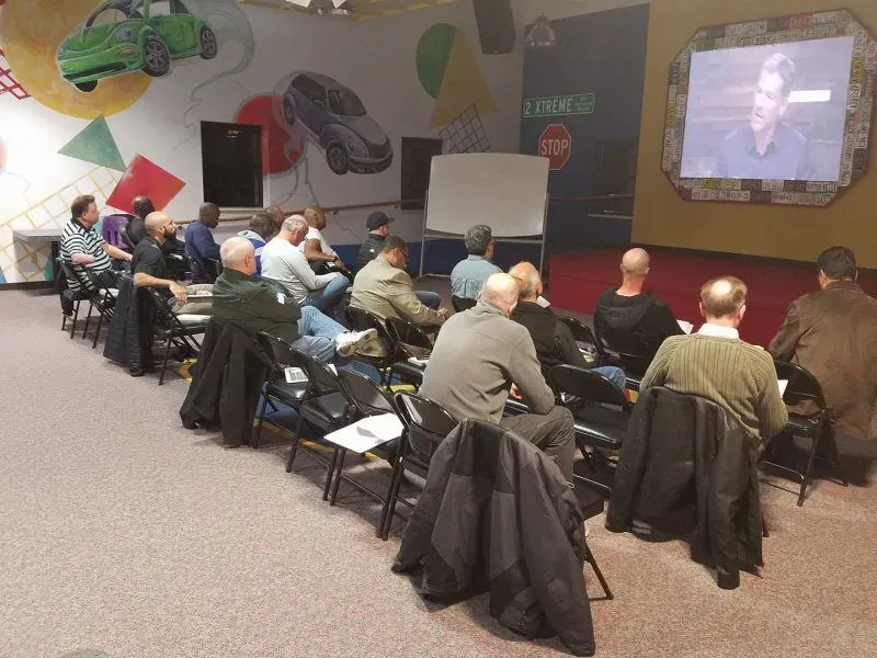 A group of people are sitting in front of a screen that says stop