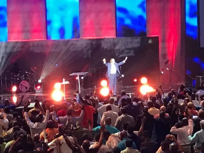 A man is standing on a stage in front of a crowd of people.