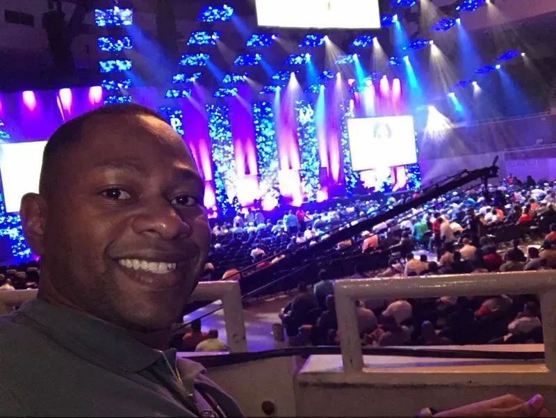 A man is smiling in front of a crowd at a concert