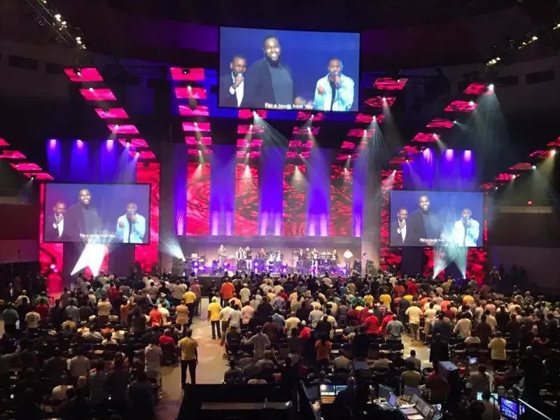 A large group of people are sitting in front of a large screen