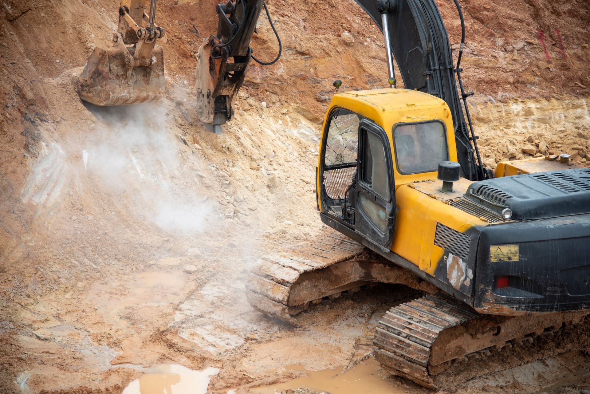 A yellow excavator is digging a hole in the dirt.