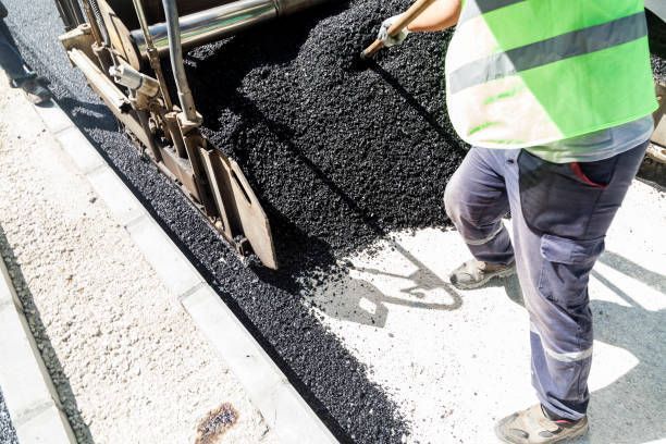 A man is spreading asphalt on a road with a shovel.