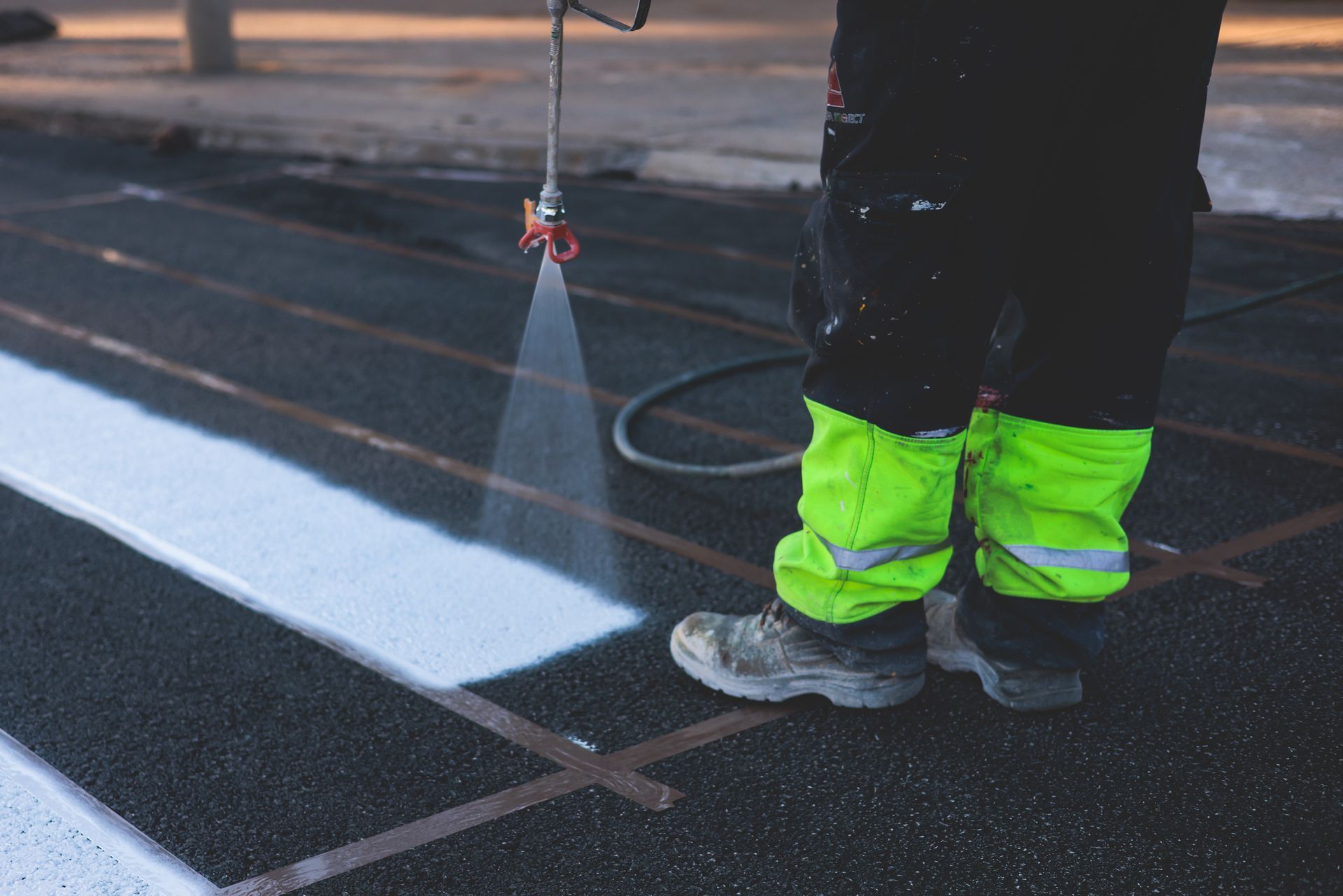 A person is spraying white paint on a road.