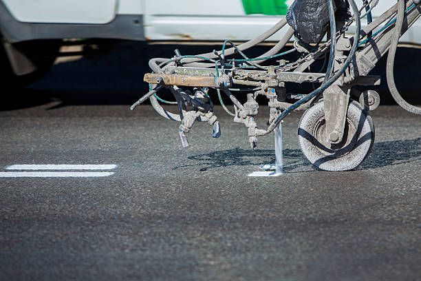 A machine is painting white lines on the road.