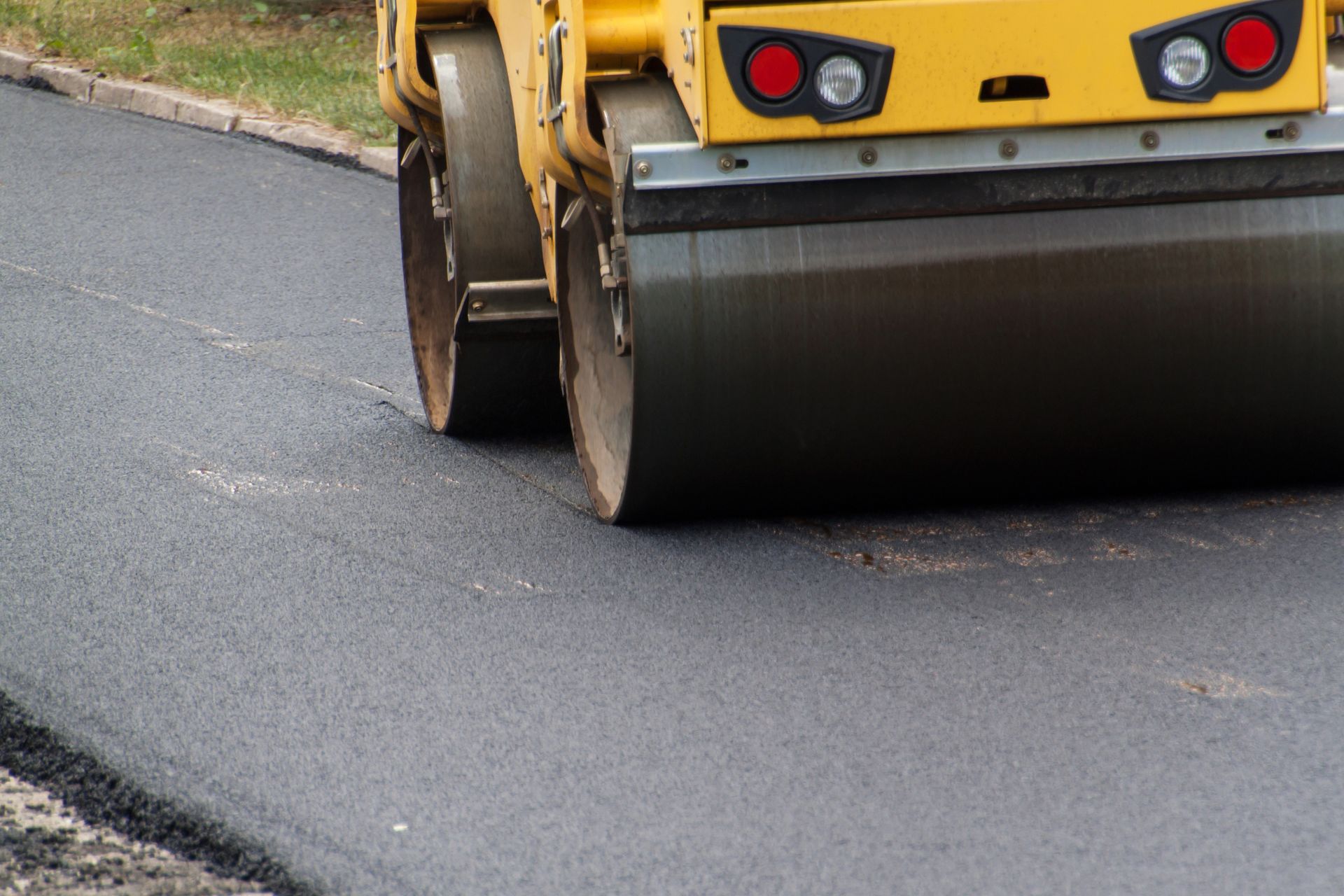 A yellow roller is rolling asphalt on a road.
