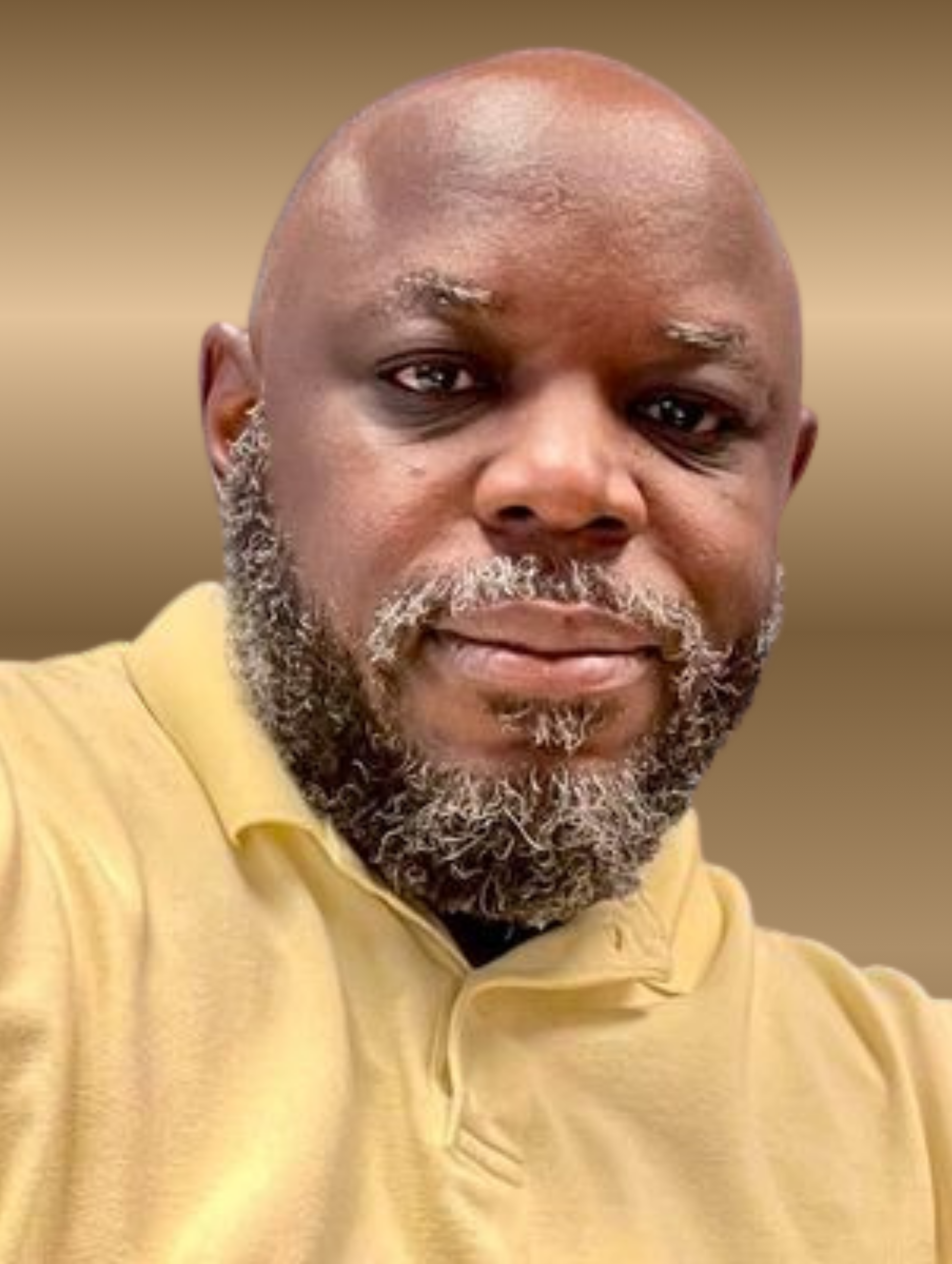 Man with a shaved head and salt-and-pepper beard, wearing a yellow polo shirt, smiling at the camera.