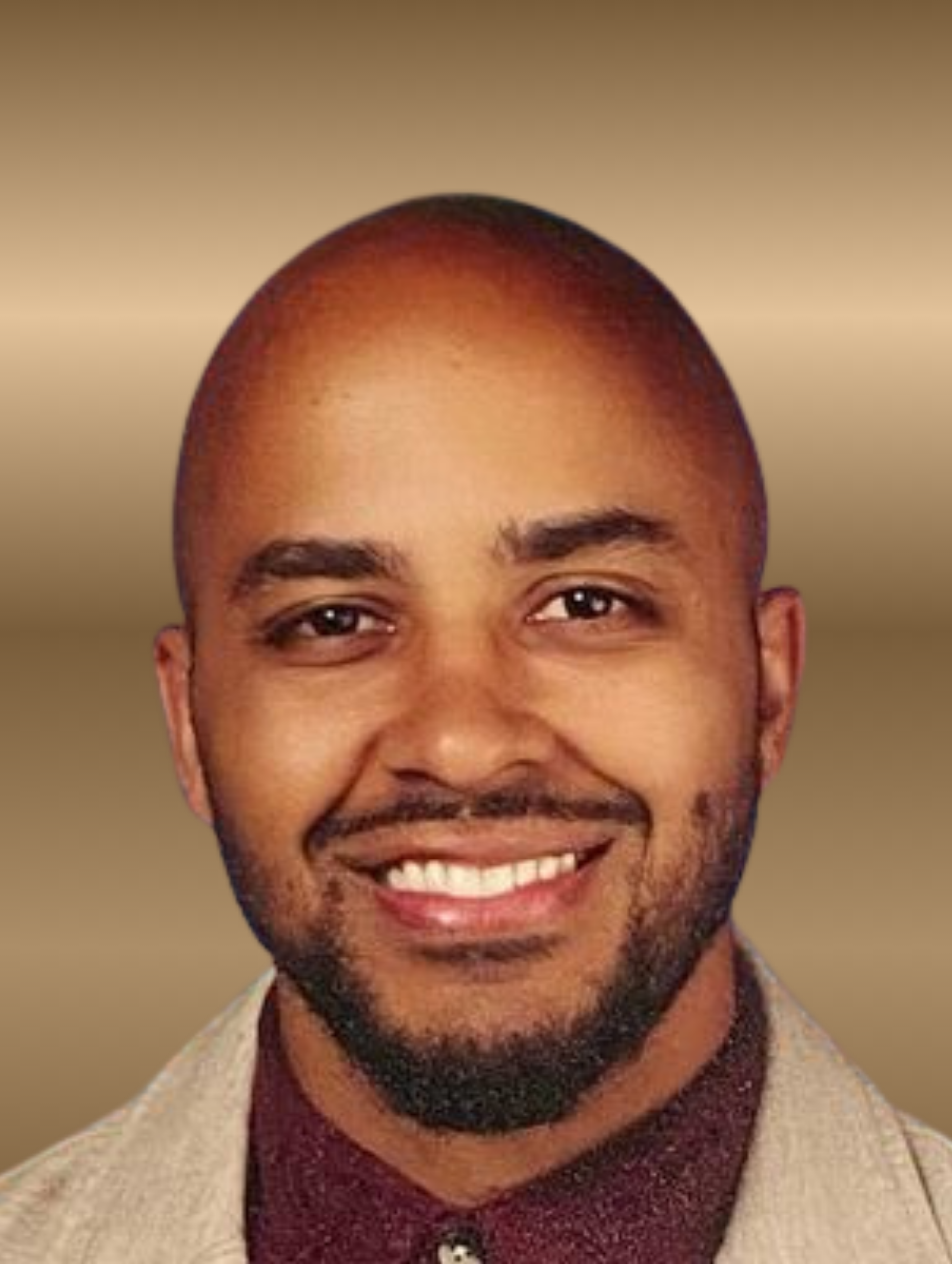 Man with shaved head and beard smiles; gold background.