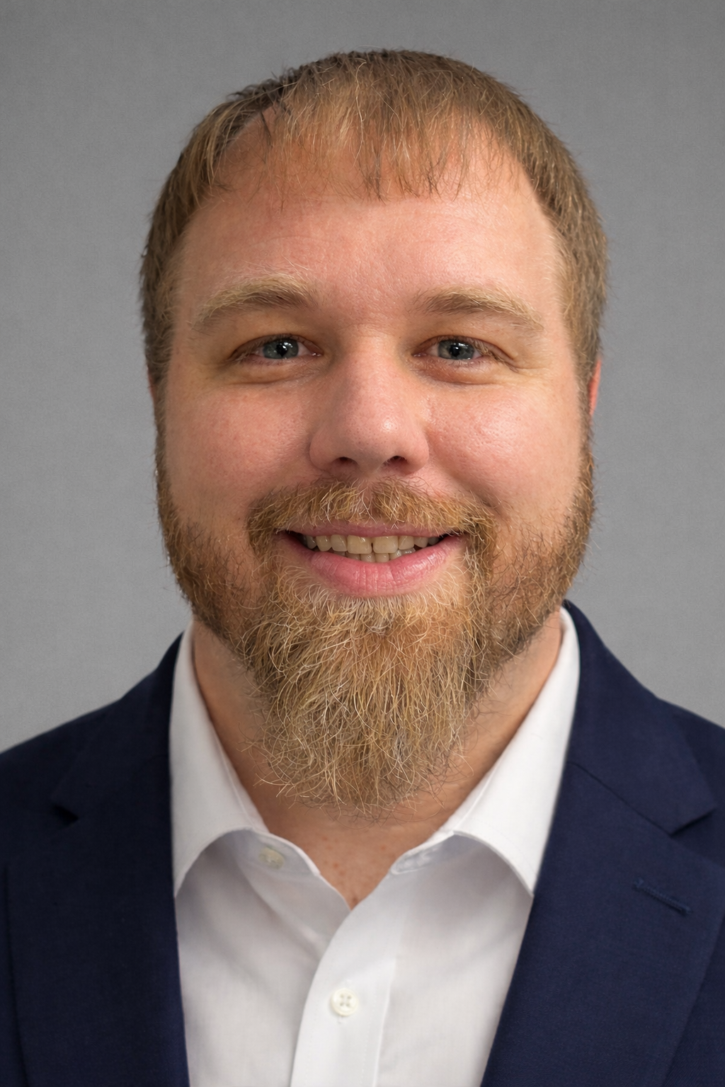 A woman is sitting at a desk with a laptop and a vase of flowers.