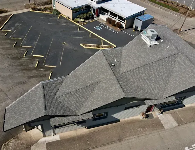 Aerial view of a gray-roofed building and a parking lot with yellow painted parking spaces.