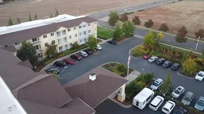 Exterior view of a multi-story building with a brown roof and a parking lot filled with cars.
