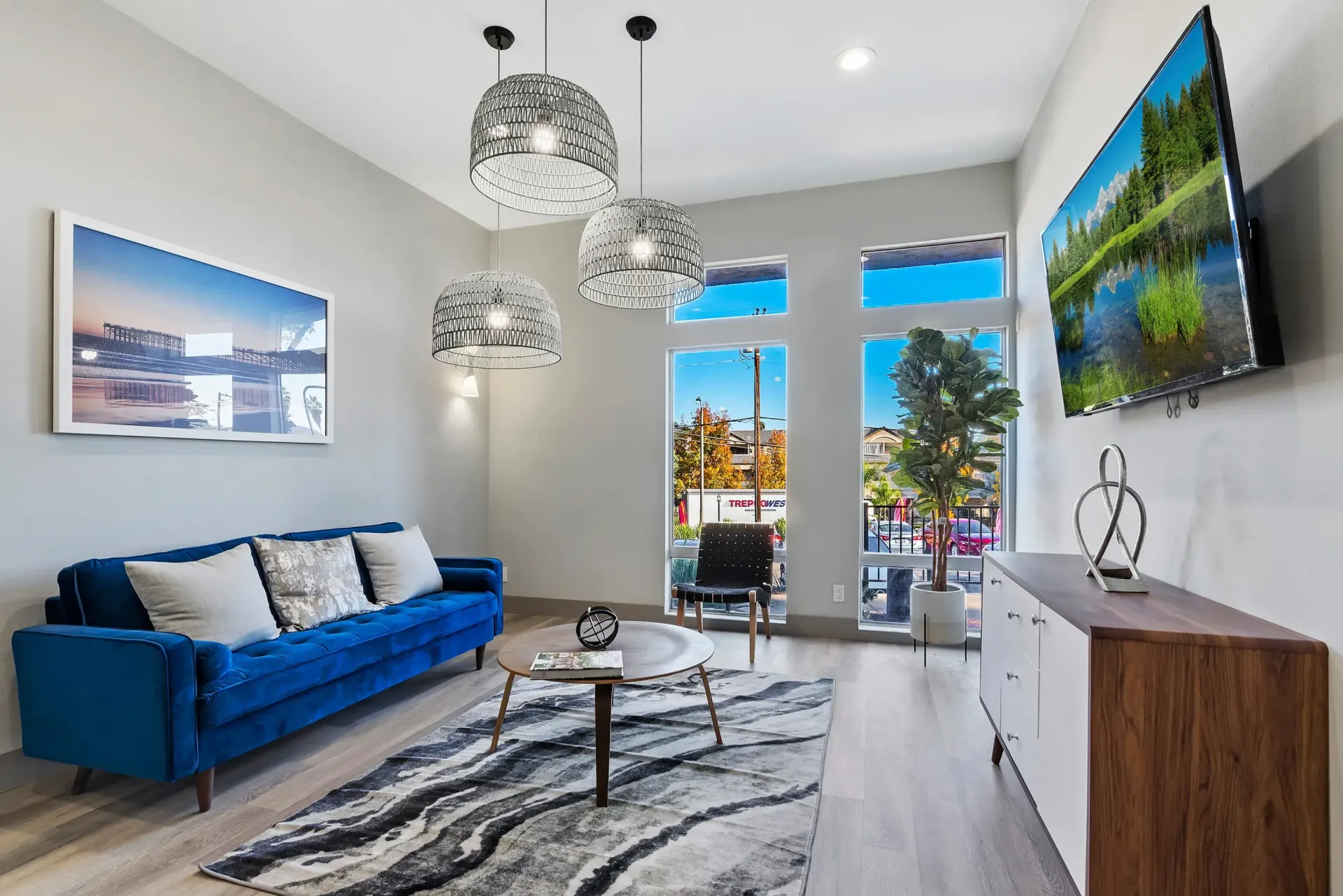 Stylish living room featuring a blue sofa, modern decor, and large windows.