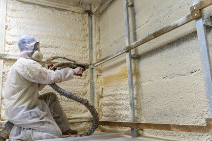 A man is spraying foam on a wall.
