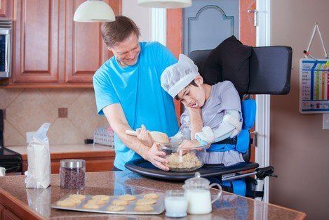 Home Care — Father Helping Disabled Son Bake Cookies in Columbus, OH