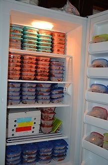 Refrigerator packed with meal-prep containers; various colors, neatly stacked on shelves.