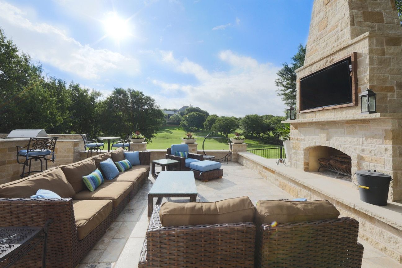 A patio with wicker furniture and a fireplace