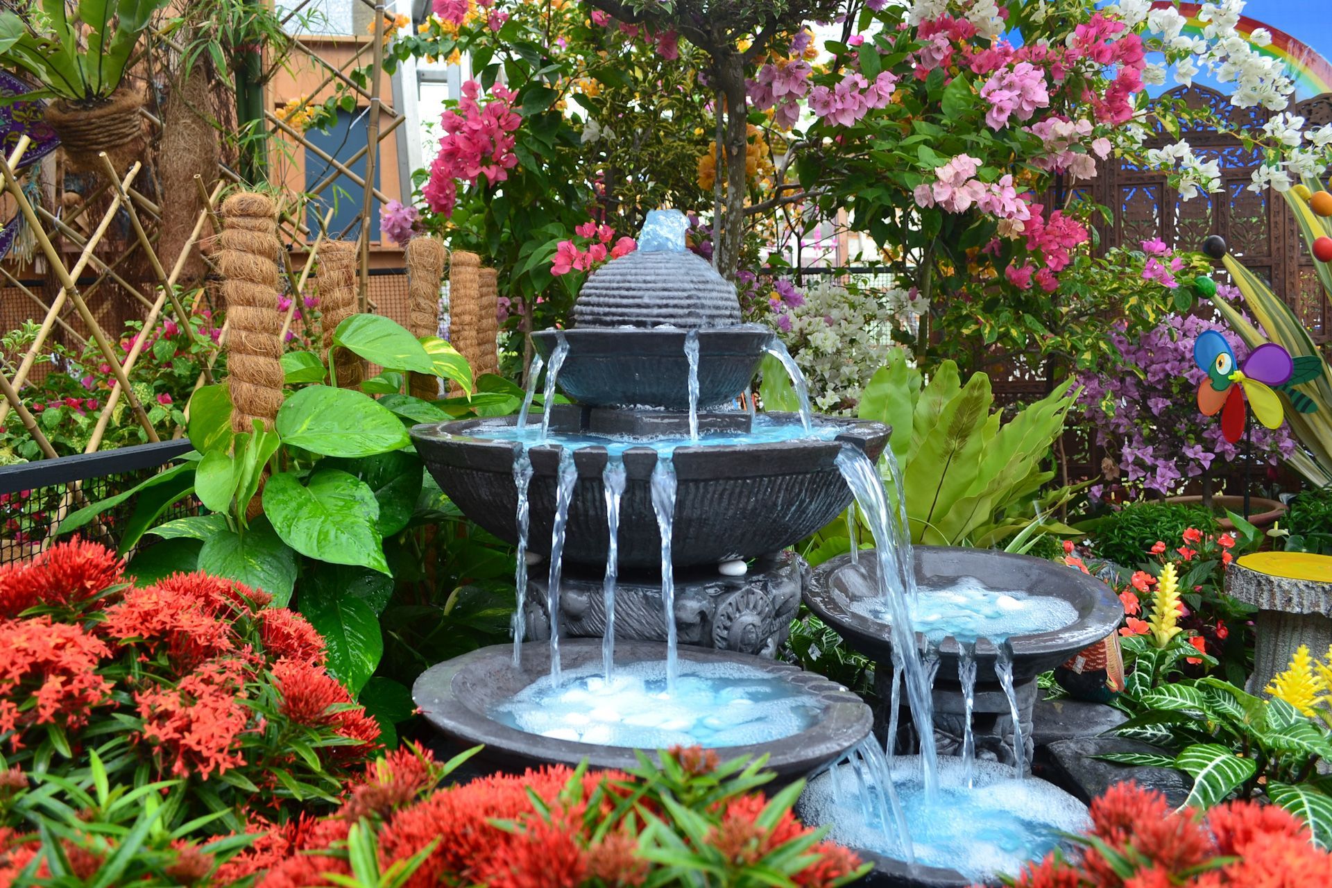 A fountain in a garden surrounded by flowers and plants.