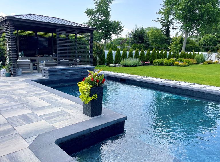 A garden with a stone wall and lots of plants and flowers.