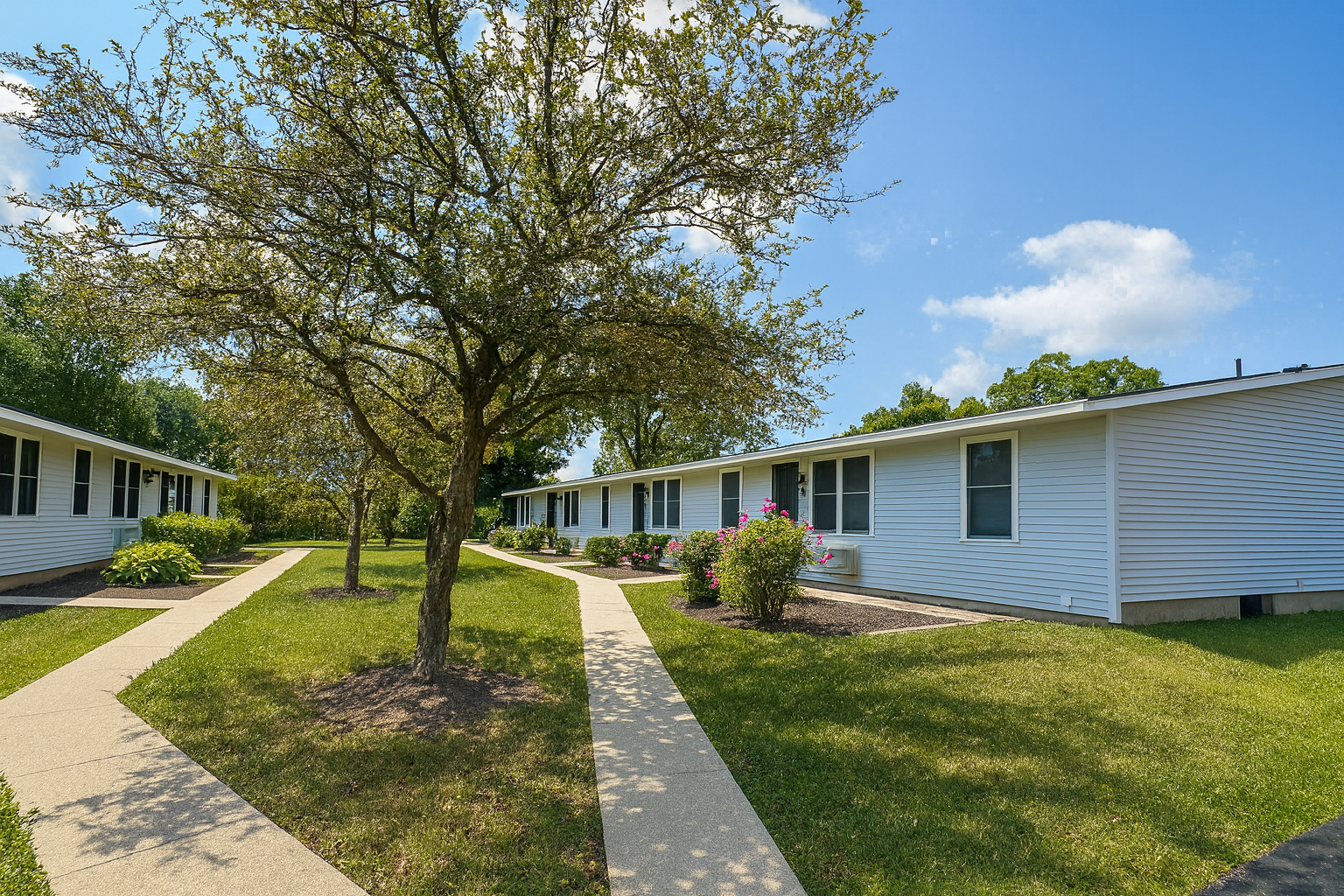 Photo of an apartmdnt community, with two single-story buildings in the photo, bungalow style