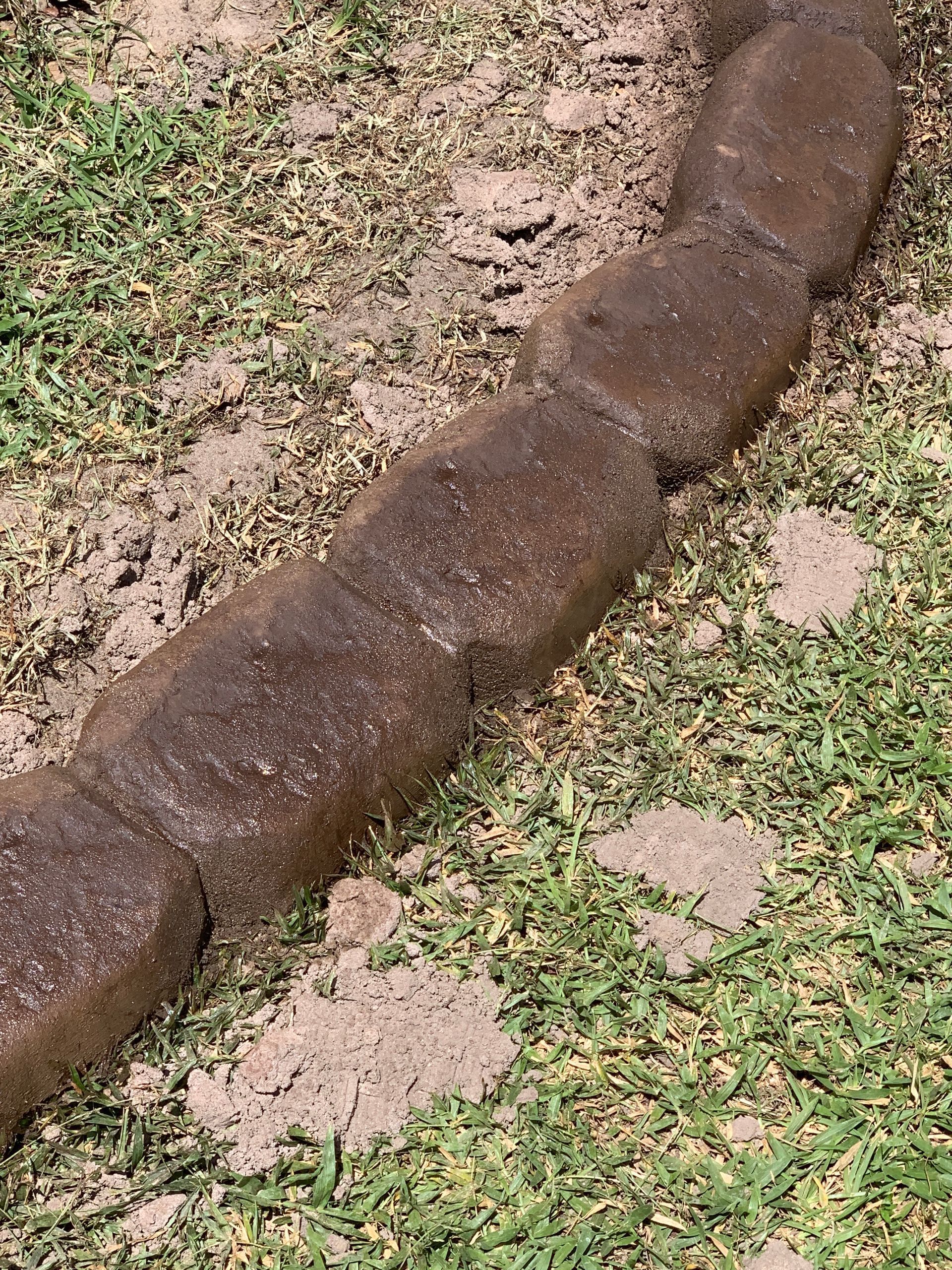 Brown, rounded stone edging along a lawn border with grass.