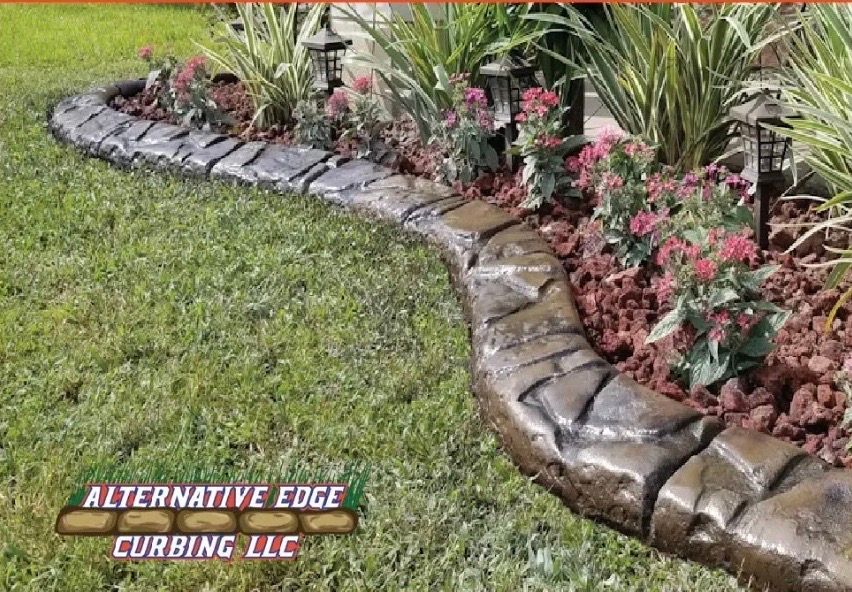 Decorative concrete curbing borders a garden bed with flowers and plants.
