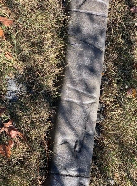 Dark, cylindrical object on grass. Appears slightly crumpled.