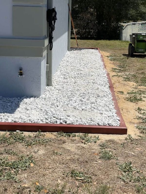 White gravel path with a brown border next to a building.